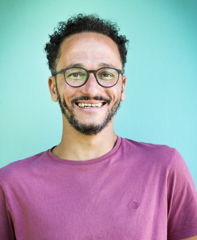 Der psychologische Berater und Coach Franz Wilhelm hat ein rosa Shirt an und l&auml;chelt. Der Hintergrund ist t&uuml;rkis.