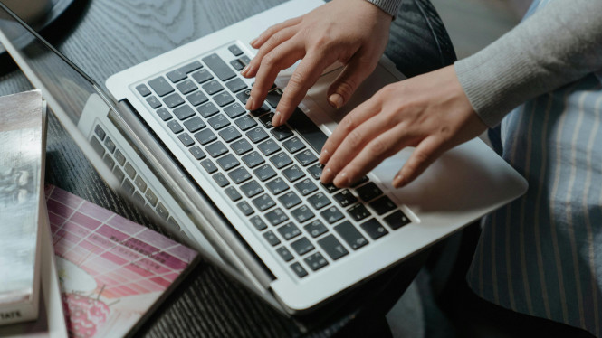 Hier ist ein Laptop zu sehen, der sinnbildlich f&uuml;r Onlinecoaching stehen soll. Ein Frau tippt einen Text.